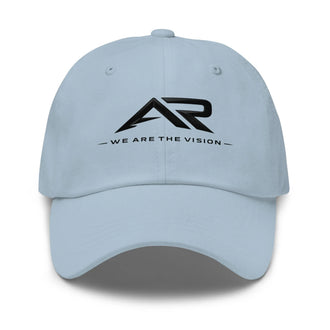 Gorra tipo dad hat azul claro con logo AR y texto 'We are the vision' en el frente.
